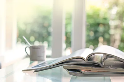 printed books in a stack on a table with a mug nearby